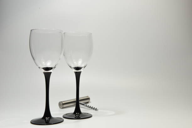 Two wine glasses with black stem and a wine bottle opener Two empty wine glasses placed side by side with a stainless steel wine bottle cork opener sabby stock pictures, royalty-free photos & images