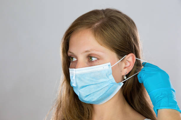 istock Young woman putting on face mask with white background. 1266424448