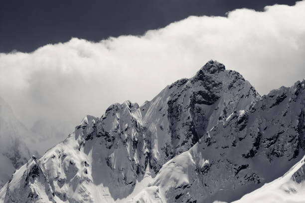 istock Black and white snowy winter mountains in cloud 1266428152