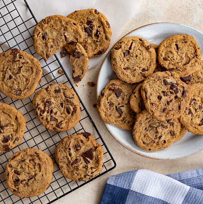 Overhead of chocolate chip cookies on a plate and cooling rack