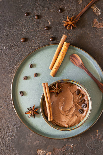 istock Coffee and chocolate pudding or mousse in a ceramic bowl with cinnamon and anise star, selective focus. Dark brown concrete background. 1266429217