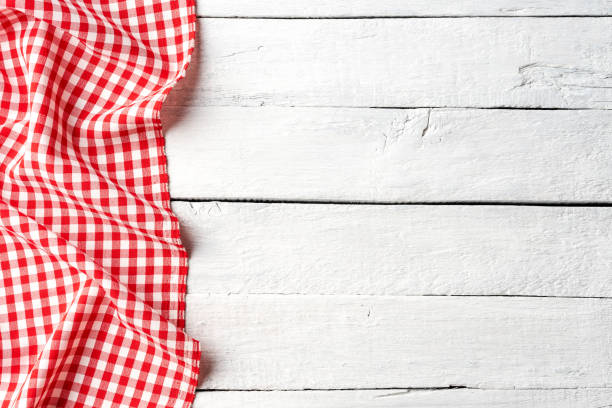 istock Red checkered tablecloth on white wooden table. Top view 1266431442