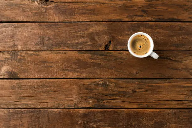 Photo of Overhead shot of hot coffee cup on wooden background with copyspace