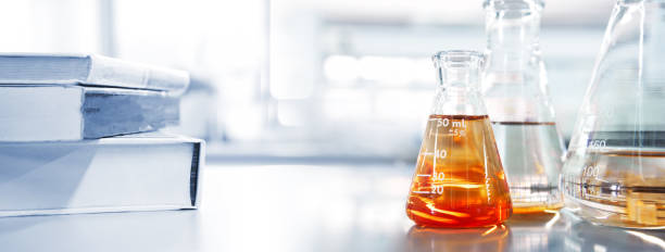 istock glass flask with orange solution and text book in chemistry laboratory school education banner background 1266434742