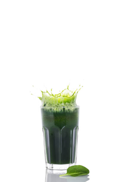 Green fresh spinach smoothie with splash in glass on white background
