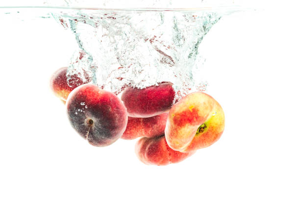 Bunch of doughnut peaches isolated on white, splashing into water.