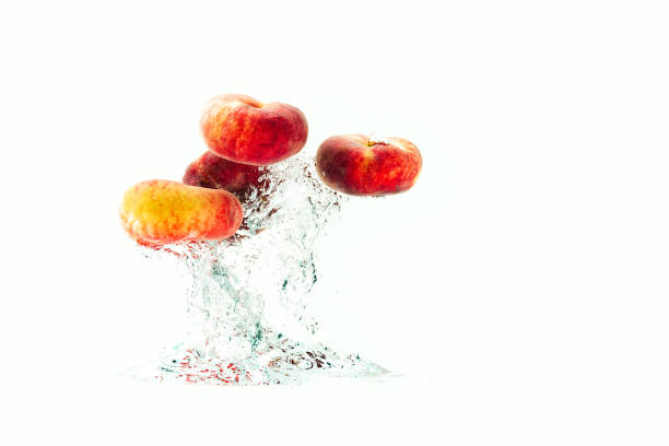 Bunch of doughnut peaches isolated on white, splashing into water.