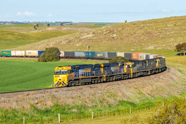 treno merci per container pesanti con cinque locomotive diesel che arrotondano la curva nei terreni agricoli collinari - rounding foto e immagini stock
