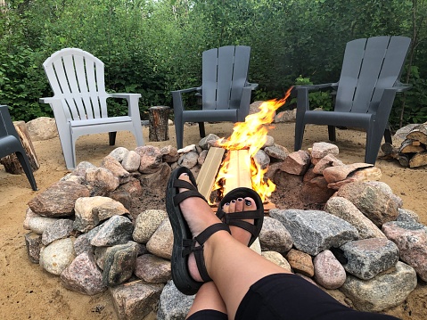 Relaxing as a fire burns in the fire pit at the cabin. Adirondack chairs are in the background.