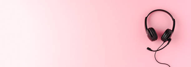 istock Call center concept. Helpdesk headset on pink desktop with copyspace. Banner 1266445149