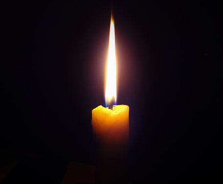 Single lit candle with quite flame on black background