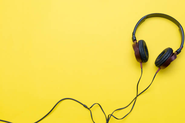 istock Modern headphones with cables on yellow background. 1266449654