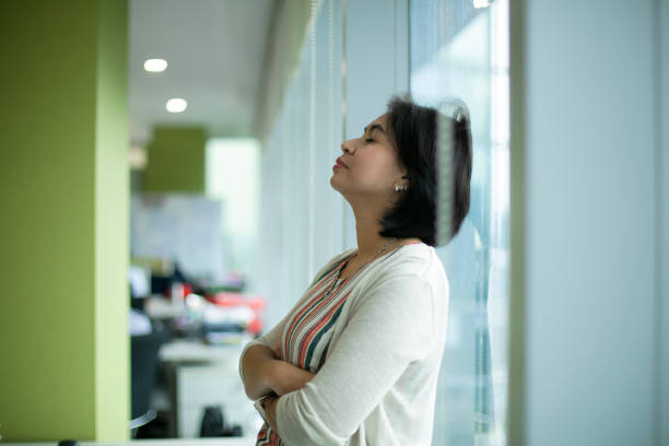 Trying to drag herself out of the doom and gloom Shot of a young businesswoman looking stressed out in an office brat stock pictures, royalty-free photos & images