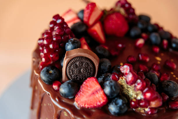 istock Appetizing chocolate cake decorated with strawberries, blueberries and a pomegranate on an orange background. 1266453802