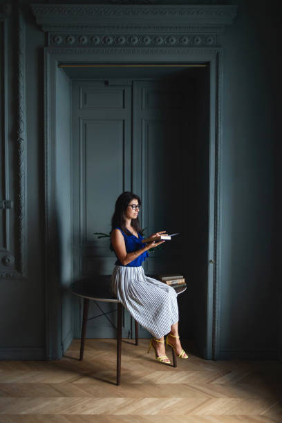 istock Woman in elegant clothes sitting on table in modern interior 1266455440