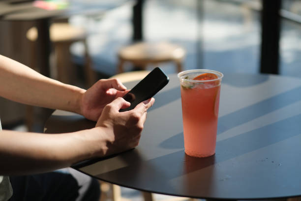 istock man's hand using smart phone in cafe, with a cup of cold drink on table 1266456034