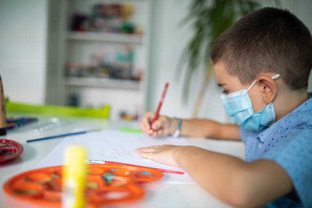 istock Boy with protective face mask drawing on art class at classroom 1266458559