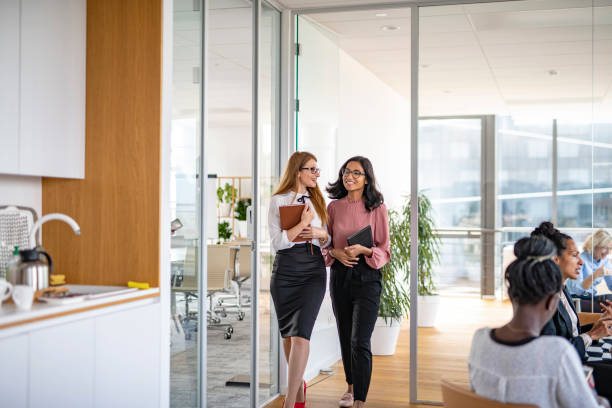 istock Smiling Businesswomen Walking Through Office and Talking 1266460779