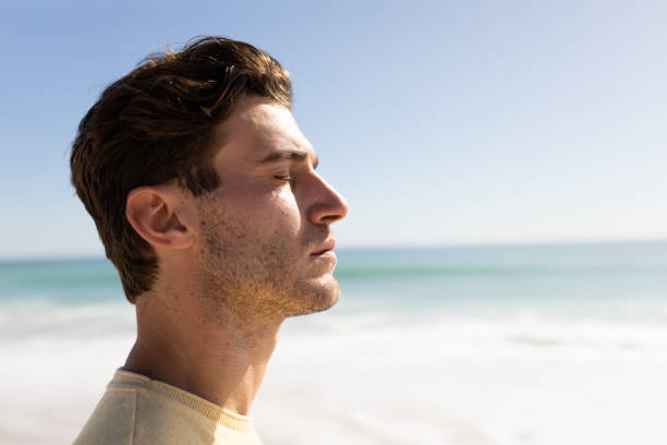 istock Young caucasian man closing eyes on the beach 1266461264