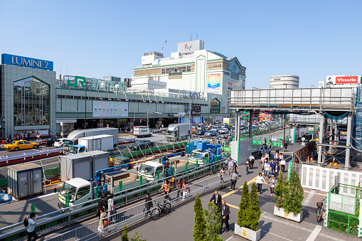 People walk past Tokyo's Shinjuku Station in Japan. It is South exit of Shinjuku Station, Tokyo, Japan. Shinjuku Station is one of the busiest train station in the world.