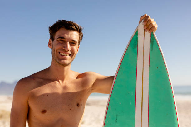 istock Caucasian man holding surf board on beach 1266462321