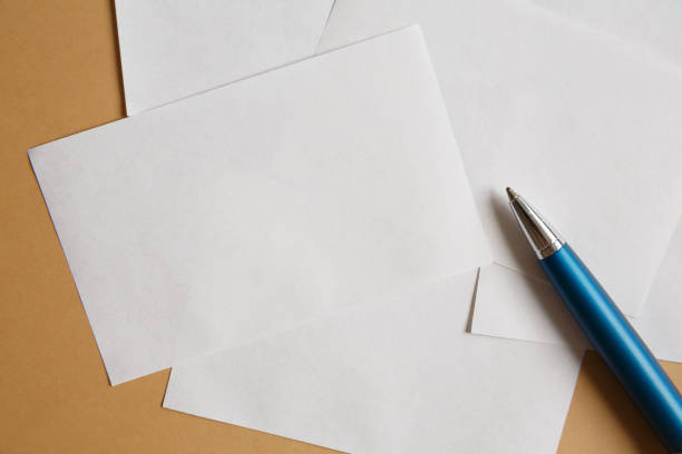 istock White small sheets of paper on a brown background and pen 1266463492