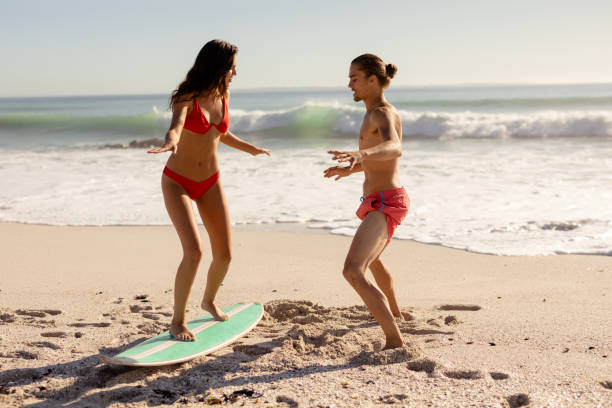 istock Young mixed race people practising surf on beach 1266463922