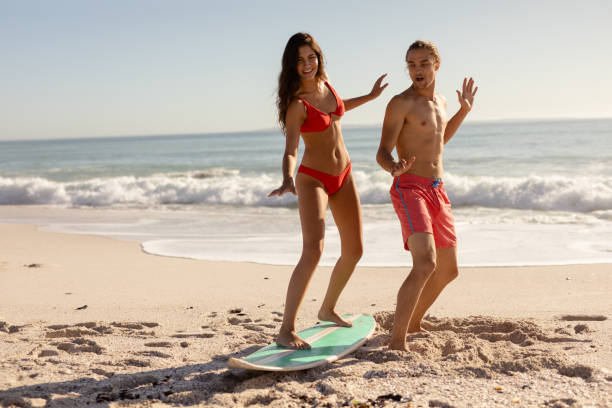 istock Young mixed race people practising surf on beach 1266463950