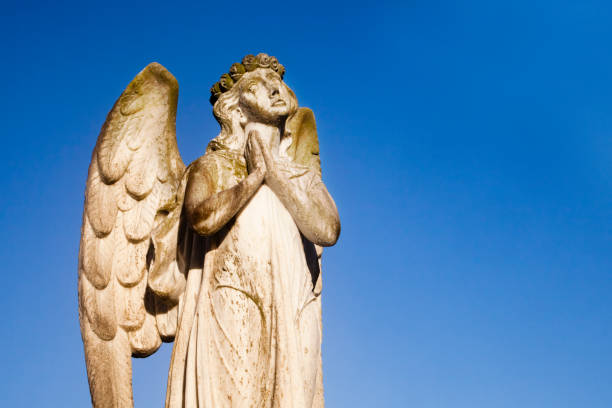 istock Ancient angel, cemetery religious sculpture on tombstone. 1266464712