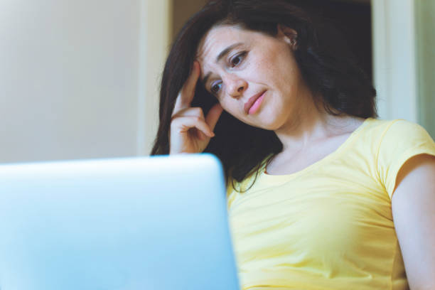 istock Distracted from work worried young woman sitting on couch with laptop, thinking of problems. Pensive unmotivated lady looking at laptop, feeling lack of energy, doing remote freelance tasks at home. 1266465813