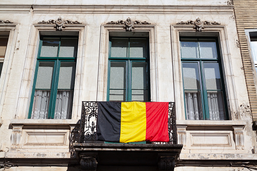Belgian flag at small balcony below 3 windows of old house in Brussels Schaerbeek