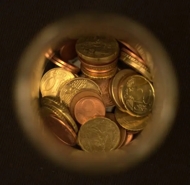 Artsy picture of euro coins in a glass container. There’s a play between focus and blur to showcase the coins