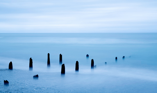 Remaining pier poles at beach at Hokitika on overcast day, South Island, New Zealand