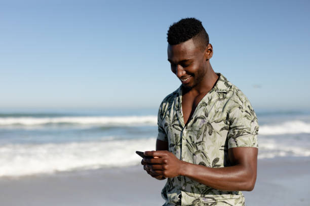 istock African american man using his phone on the beach 1266468851