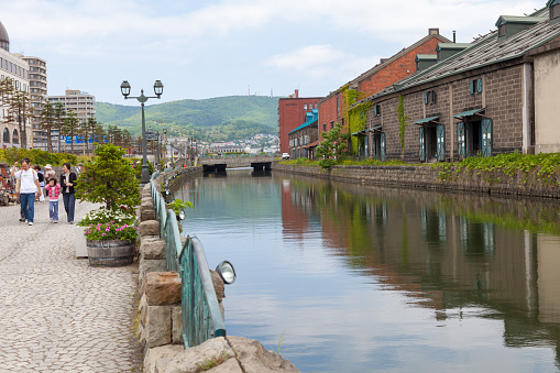People visiting Otaru Canal in Oraru, Hokkaido, Japan. Many warehouses are on the canal. Otaru Canal is the symbol in Hokkaido. In Meiji Period, Otaru was the significant port in Hokkaido. Nowadays, the canal became a tourist attraction.