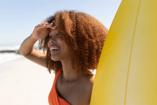 istock Mixed race woman holding a surfboard  on the beach 1266469948