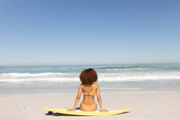 istock Mixed race woman sitting on the beach 1266470029