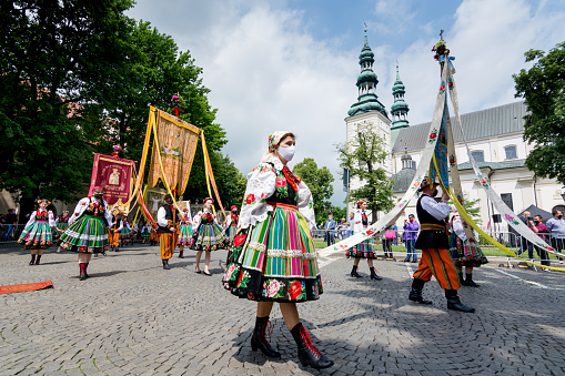 Lowicz, Jun 11, 2020: People dressed in polish national folk costumes and face protective masks during Corpus Christi procession. Traditional colorful folk embroidered dress