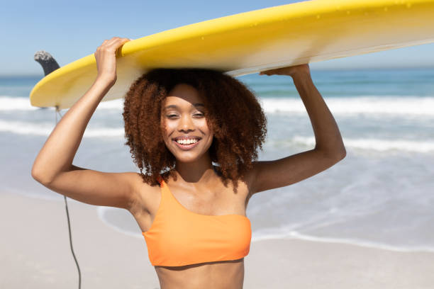 istock Mixed race woman holding a surfboard  on the beach 1266470848
