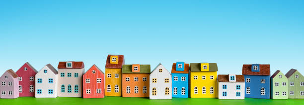 Row of wooden miniature colorful retro houses on blue background Colorful miniature houses arranged in a row on blue background. Urban city background banner. Copy space tiny house photos stock pictures, royalty-free photos & images