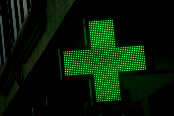 primo piani del simbolo della farmacia in strada, edifici, croce verde. - green cross foto e immagini stock