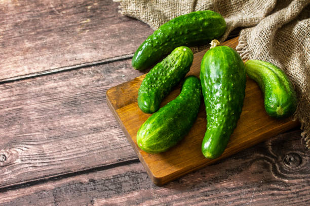 istock Fresh vegetable. Ugly organic twisted cucumbers on wooden table. Copy space. 1266481353