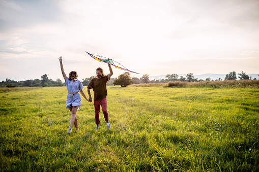 Happy young couple launch a kite on nature at sunset