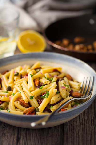 Home made freshness caramelized red onions with casarecce pasta,roasted almond,capes and sun dried tomatoes in a bowl.it is a simple gluten free,milk free,egg free and soya free dish.