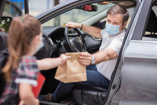 istock Man with mask giving his daughter school lunch 1266484987