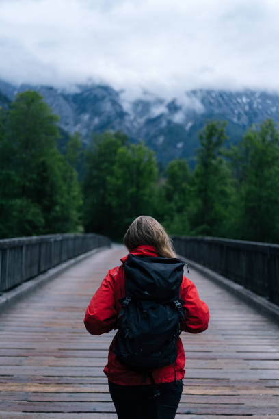 istock Young woman backpacker hikes across bridge in the forest 1266488939