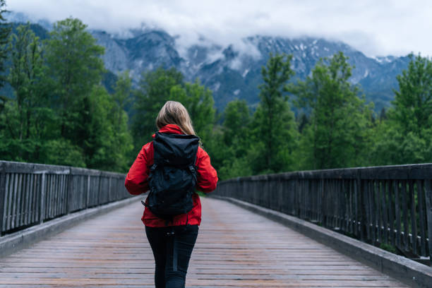 istock Young woman backpacker hikes across bridge in the forest 1266489065