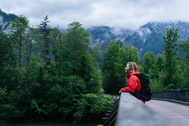istock Young woman backpacker hikes across bridge in the forest 1266489890
