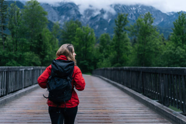 istock Young woman backpacker hikes across bridge in the forest 1266490047