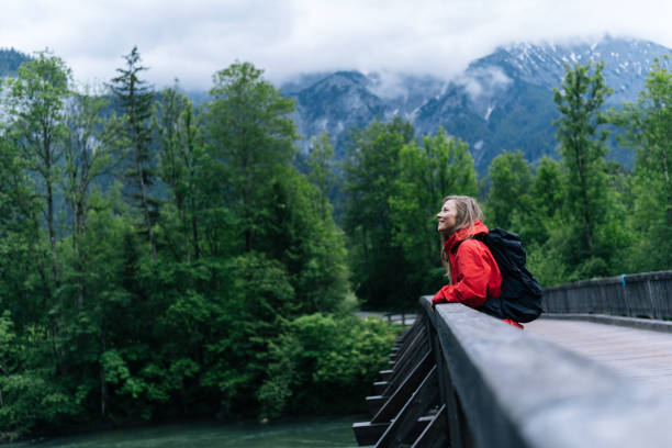 Young woman backpacker hikes across bridge in the forest